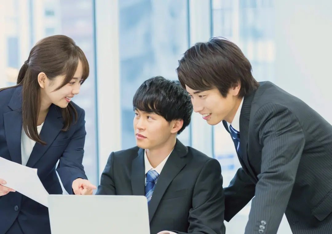 パソコンを囲んで打ち合わせをする3人のビジネスパーソン