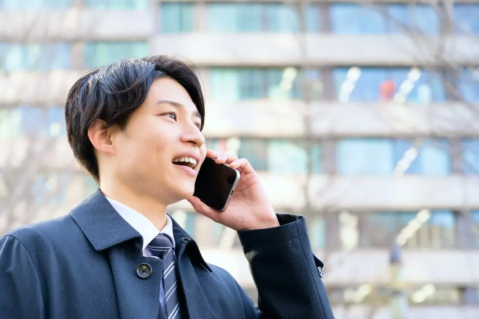 スマートフォンで笑顔で話すビジネスパーソン